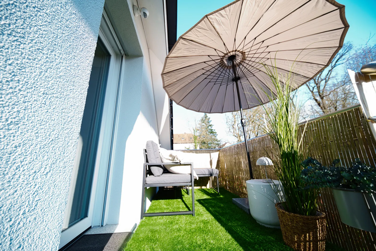 Sitzplatz mit Sonnenschirm und Rasen