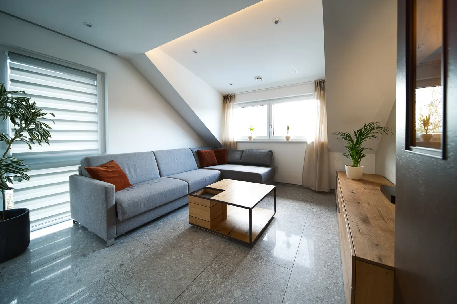 Wohnzimmer mit grauem Sofa und Steinboden